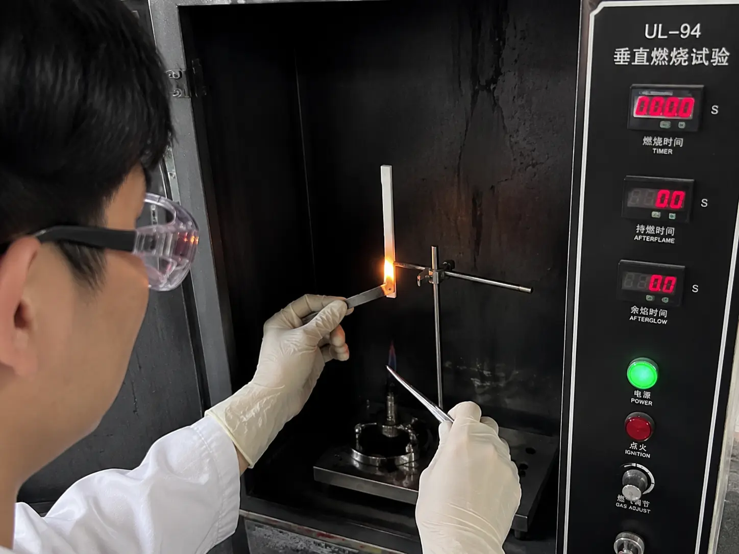 Technician performing a live UL94 vertical burn test in the QC lab
